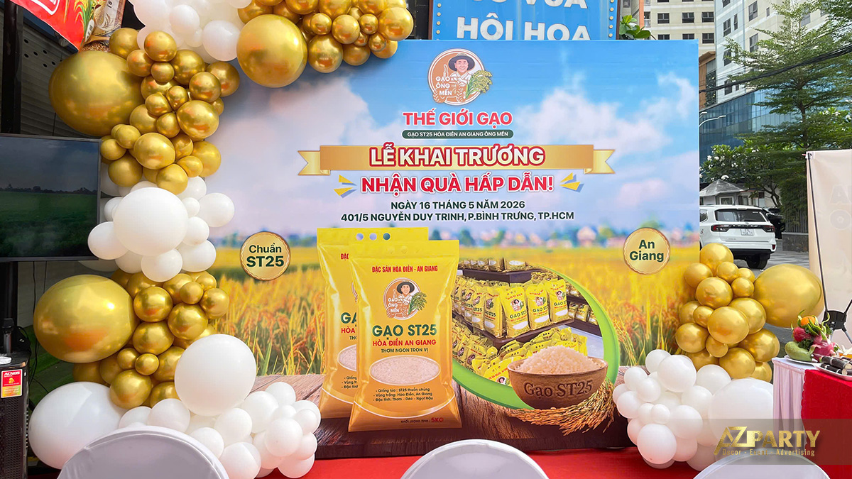 Backdrop lễ khai trương Thế Giới Gạo ST25 Hòa Điền An Giang với chương trình nhận quà hấp dẫn và bong bóng vàng trắng
