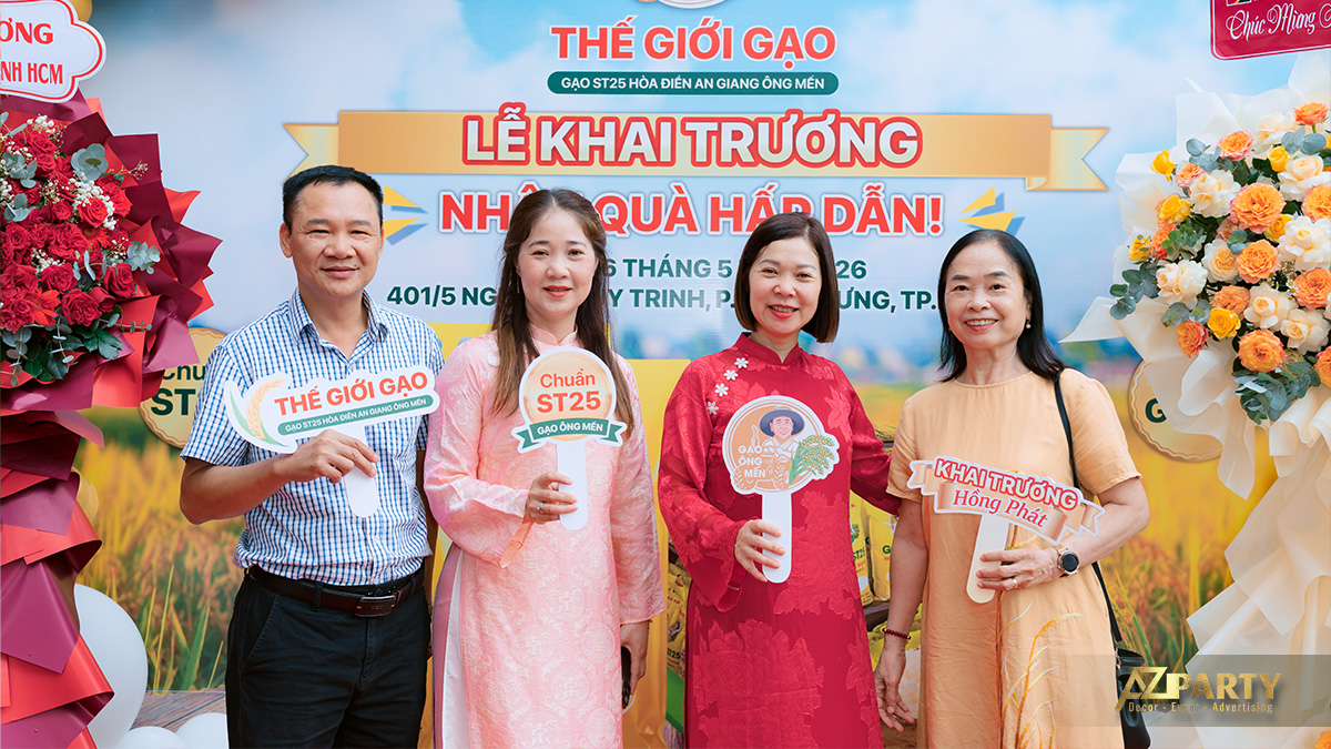 Khách mời chụp ảnh lưu niệm với backdrop khai trương Thế Giới Gạo ST25 Chuẩn Hòa Điền An Giang trước backdrop