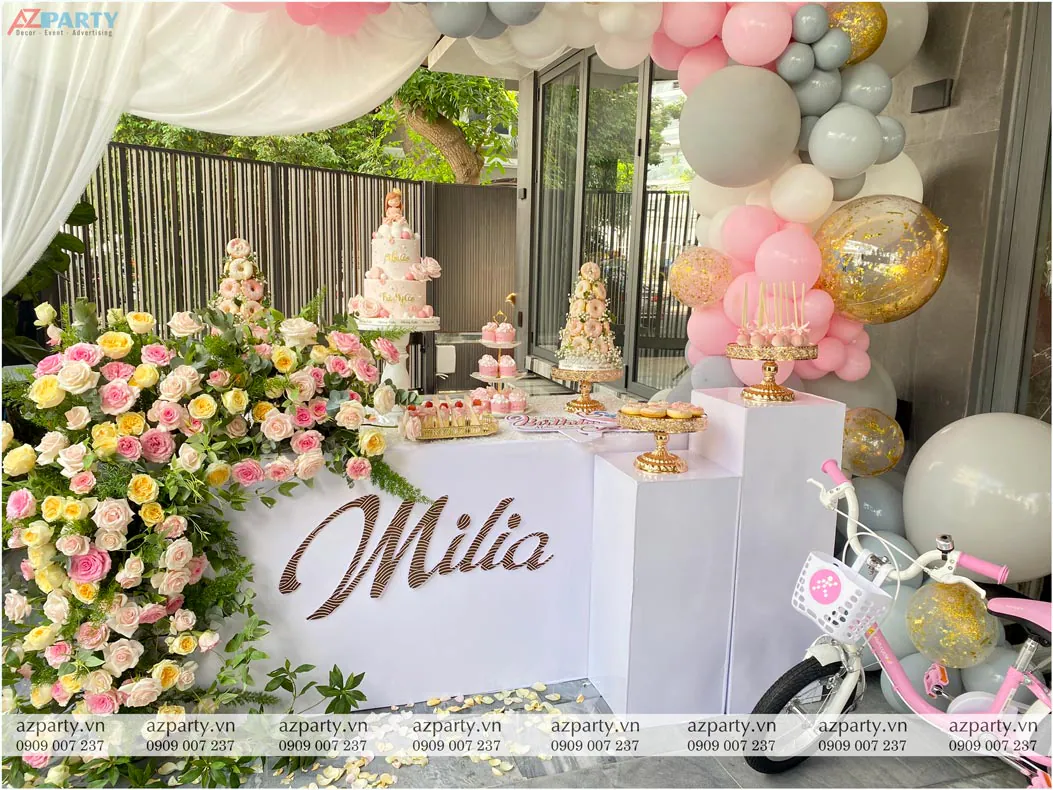 Bàn tiệc ngọt ngập tràn các khay bánh donut, cake pops đặt cạnh chiếc xe đạp hồng dễ thương phía trước rèm voan trắng rủ tự nhiên.