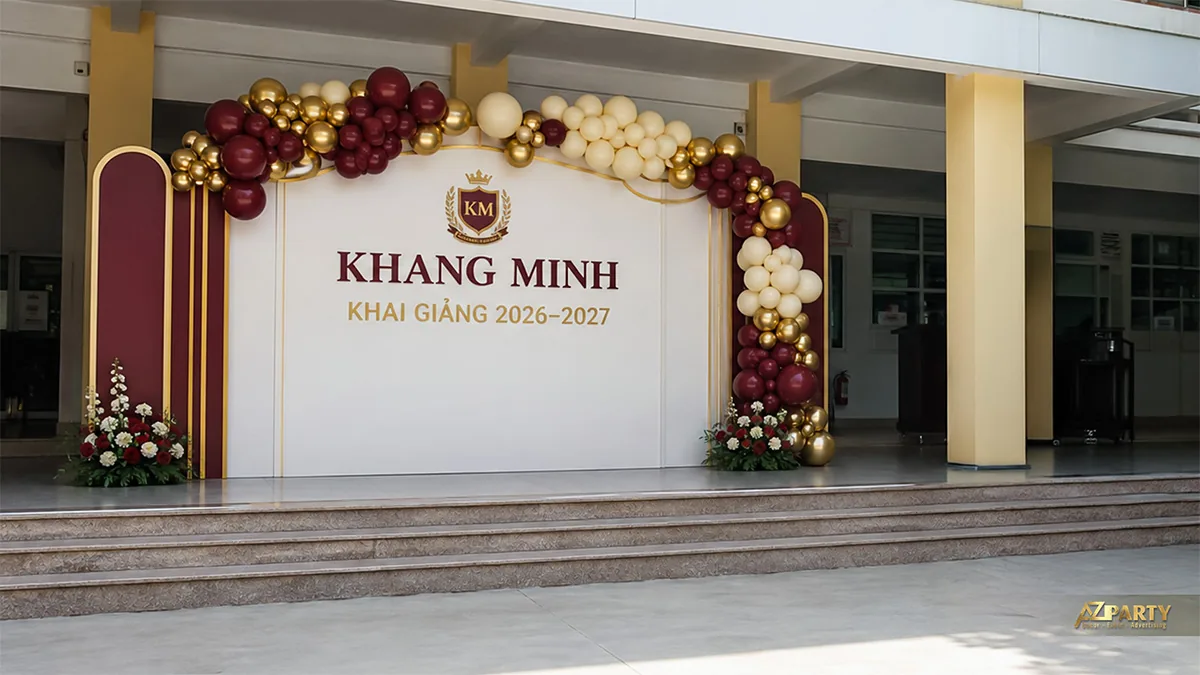 Backdrop khai giảng Khang Minh màu đỏ đô kem với vòng bóng chạy phía trên