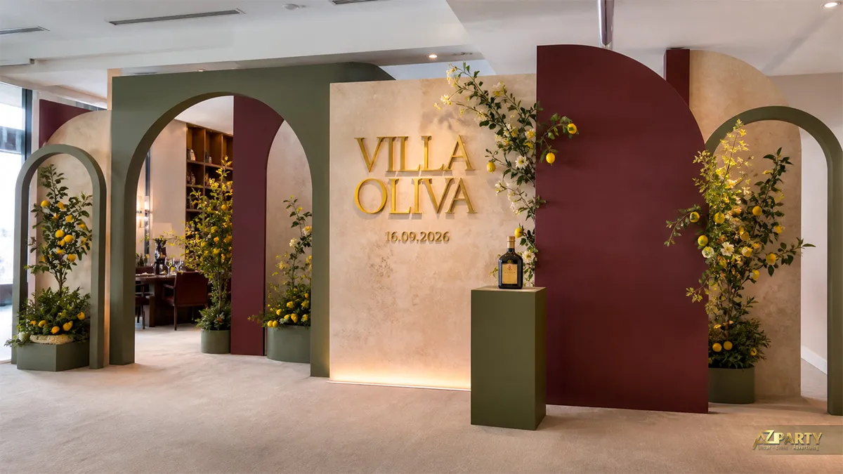 Backdrop Villa Oliva phối vòm xanh olive đỏ rượu với cây chanh và bục trưng bày dầu
