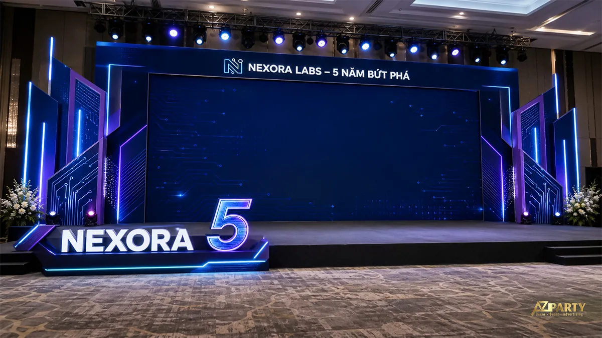 Sân khấu kỷ niệm 5 năm Nexora Labs với khung mạch điện xanh tím