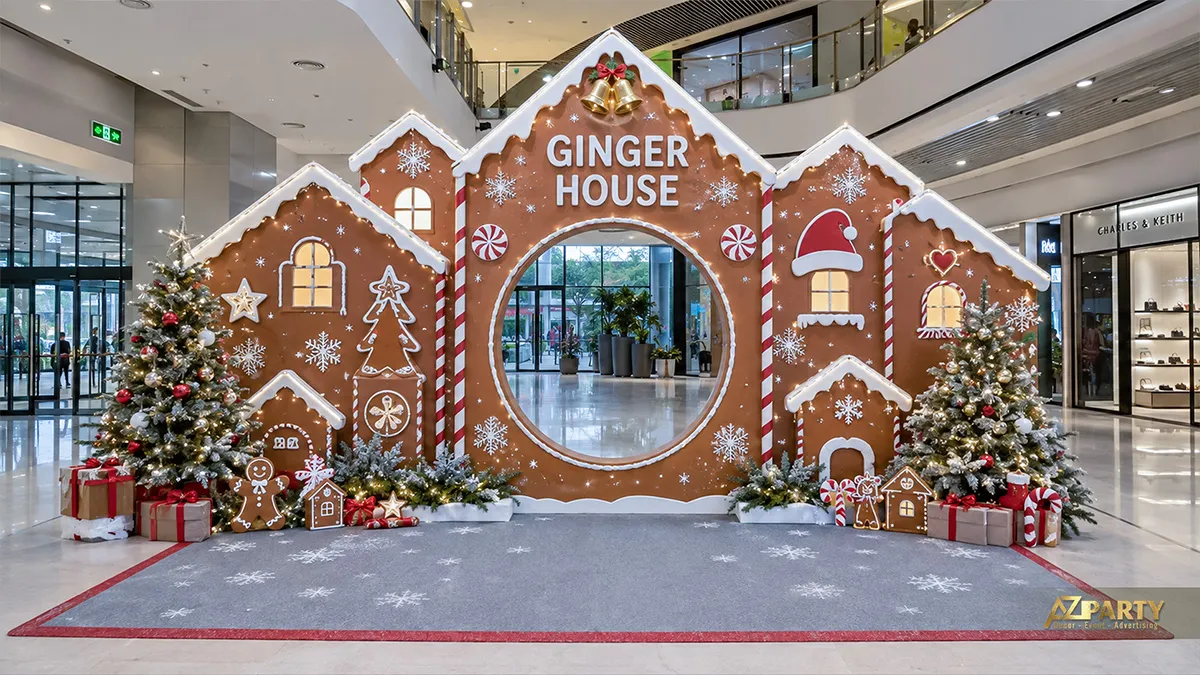 Booth Noel mô phỏng ngôi nhà bánh gừng với ô cửa tròn, cây thông, hộp quà và thảm đỏ