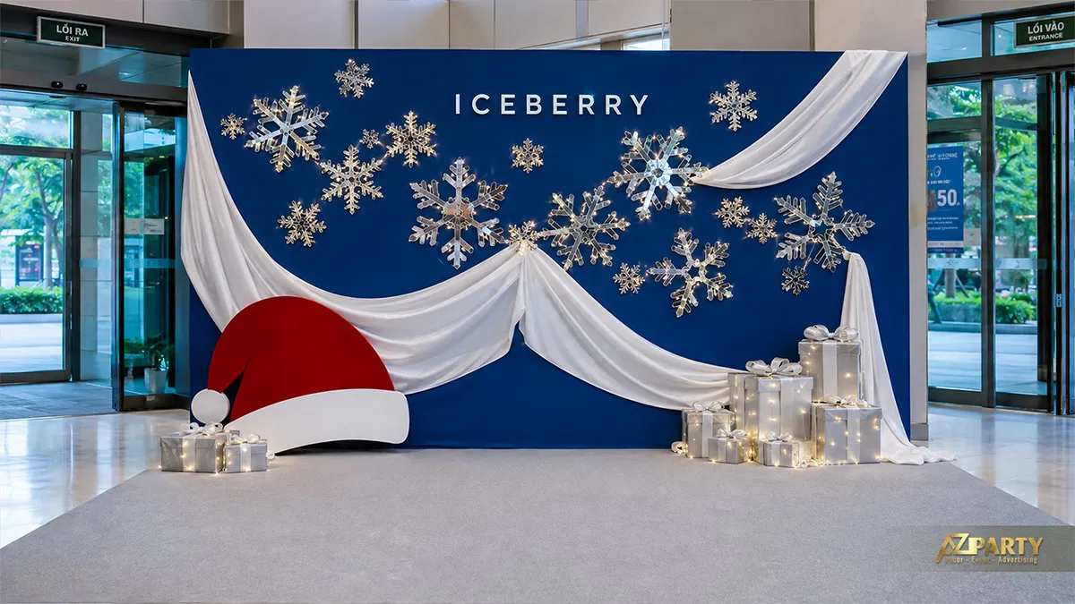Backdrop Noel xanh trắng với rèm vải mềm, cụm bông tuyết treo, mũ ông già Noel và nến trang trí