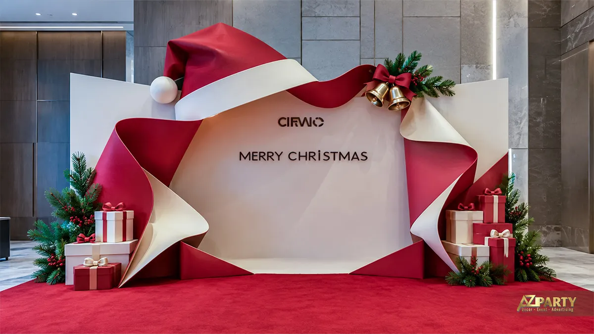Backdrop Noel dạng khung gấp góc màu đỏ trắng với nơ lớn, chuông vàng, hộp quà và thảm đỏ