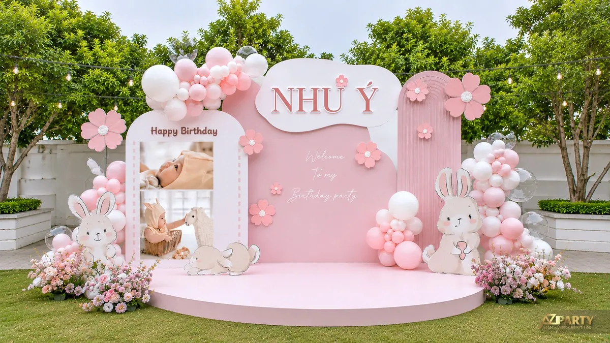 Backdrop sinh nhật bé Như Ý màu hồng với bóng trắng, thỏ và cụm hoa trang trí