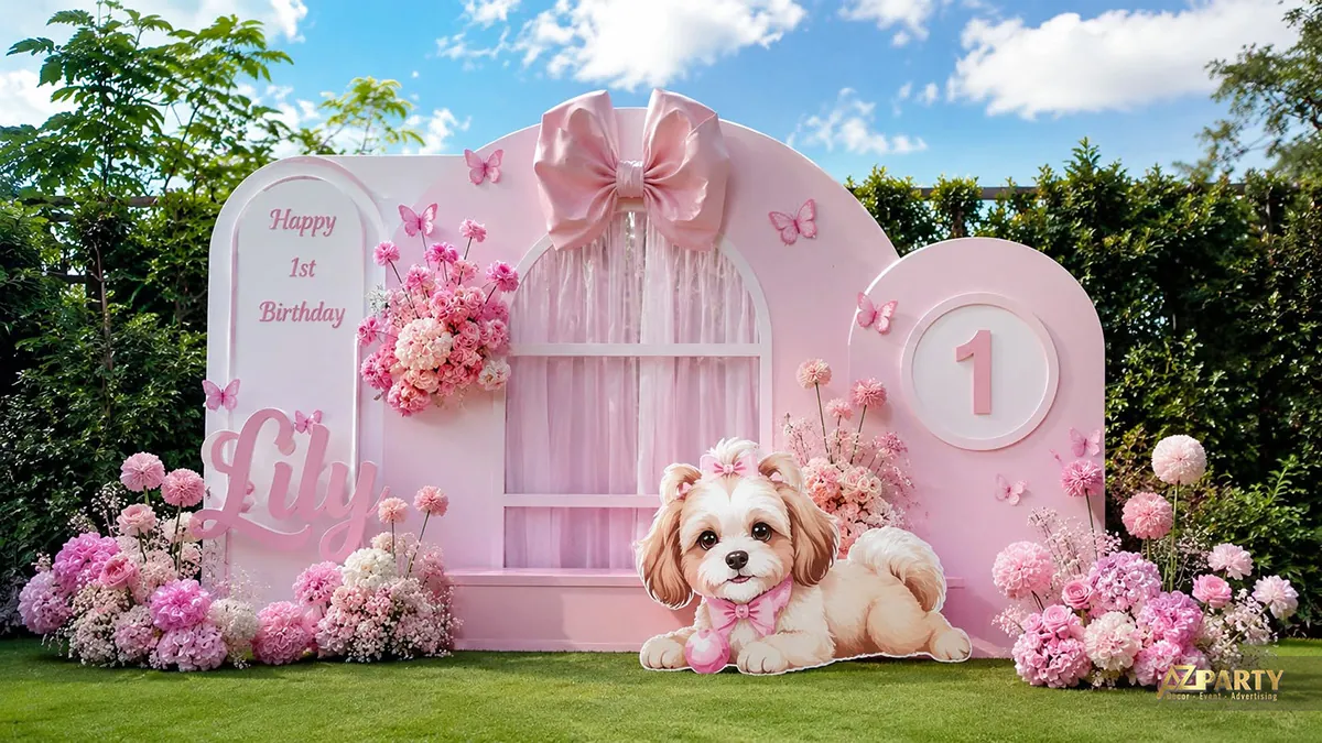 Backdrop thôi nôi màu hồng ngoài trời với nơ lớn, hoa, bươm bướm và chú cún