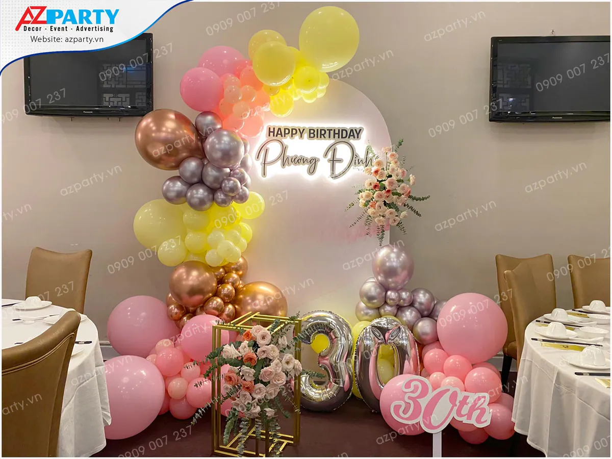 Không gian trang trí sinh nhật tuổi 30 của Phương Đình với backdrop tròn chữ nổi phát sáng, bong bóng màu hồng, vàng nhạt, bạc metallic sang trọng.