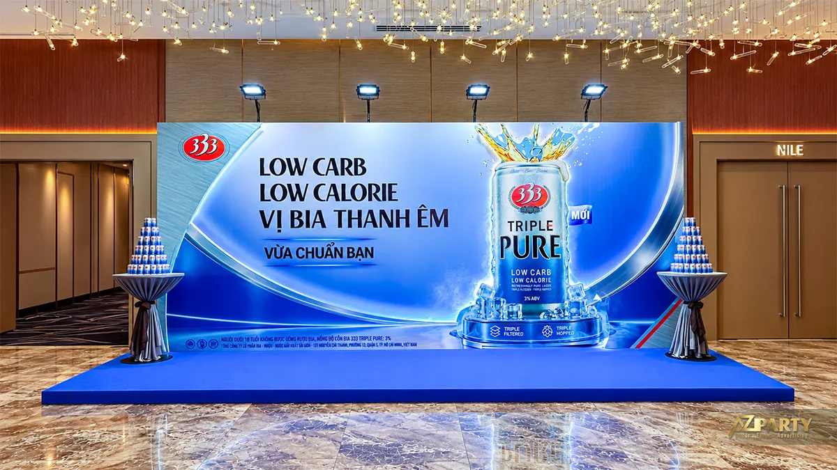 Booth 333 Triple Pure chụp chính diện với nền xanh bạc và hai bàn trưng bày lon bia