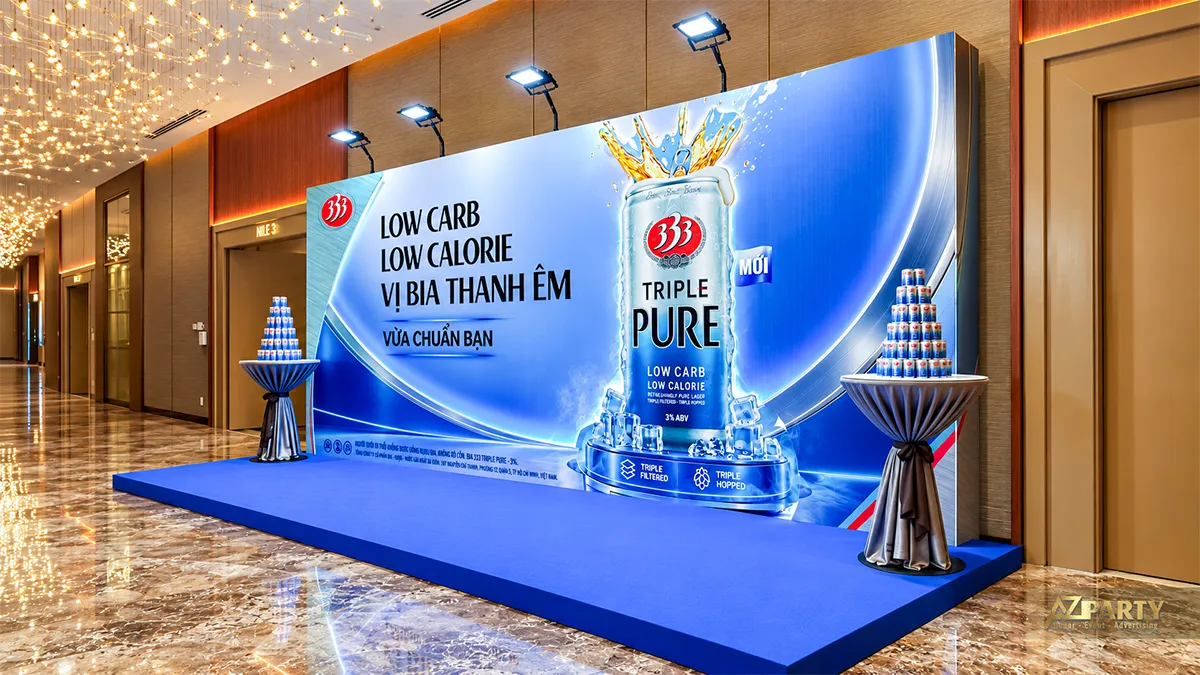 Góc bên phải với hình lon 333 Triple Pure lớn và tháp lon trên bàn phủ khăn bạc