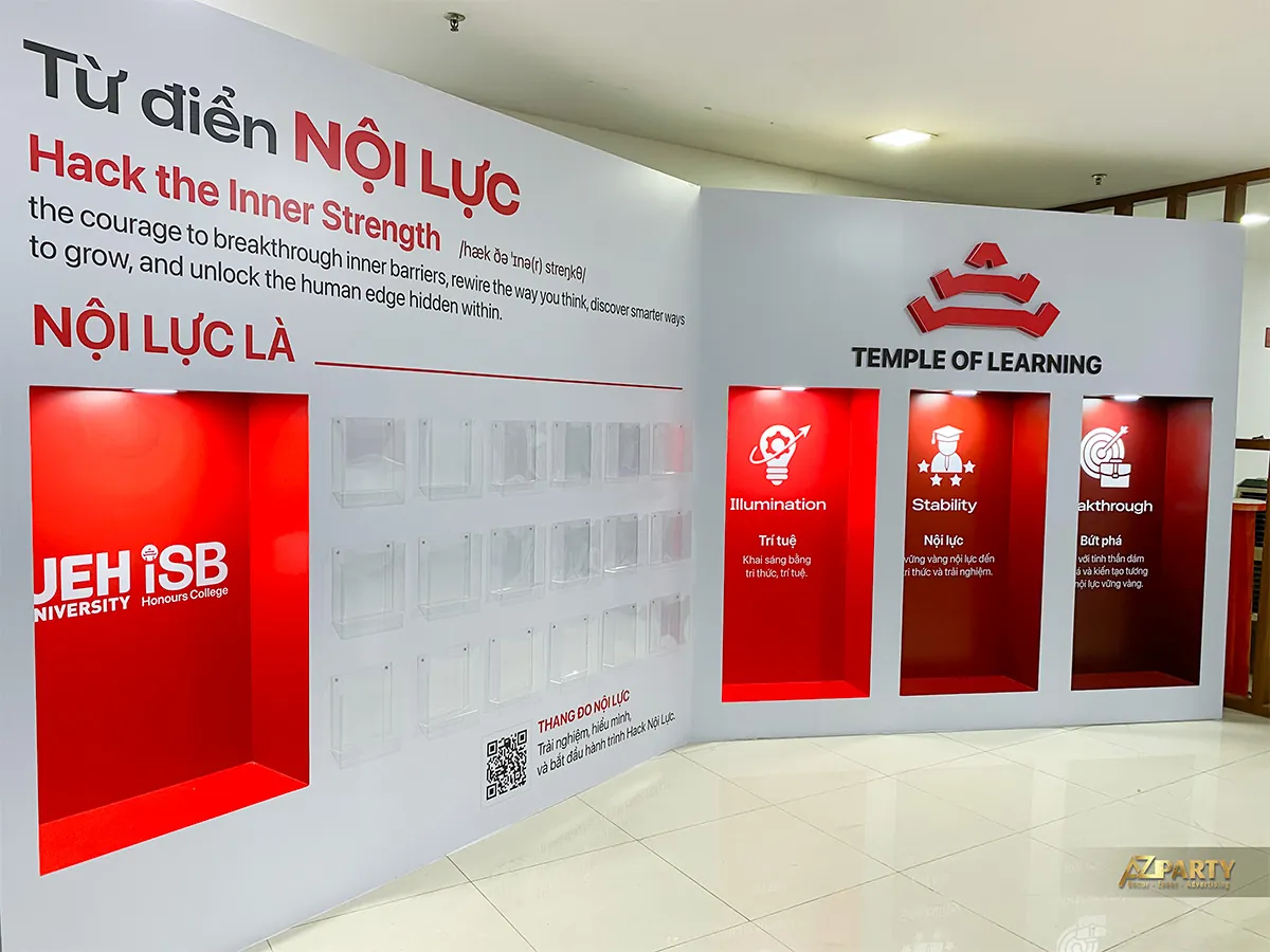 Góc rộng booth check-in UEH.ISB với vách trắng, các hốc đỏ và khu Thang đo Nội lực