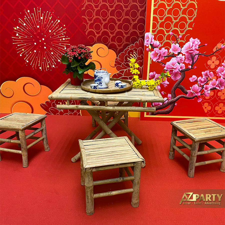 Cận cảnh bộ bàn ghế tre nhỏ mộc mạc đặt trên thảm đỏ, bày biện khay ấm chén bằng gốm sứ trắng xanh vẽ hoa văn cúc vàng điểm tô ngày Tết.