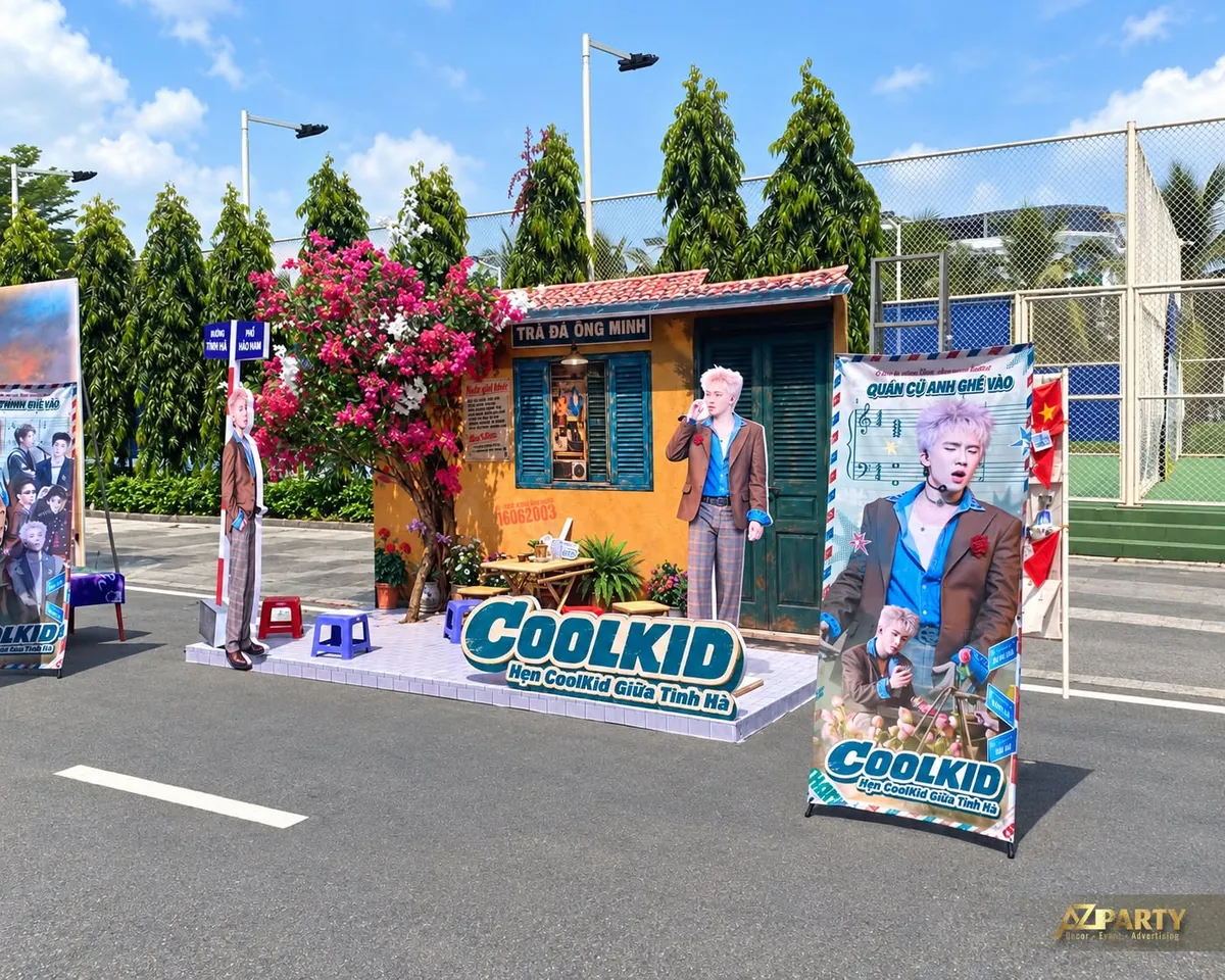 Góc phải booth với bảng ảnh Coolkid, bàn trà nhỏ và biển Trà đá Ông Minh