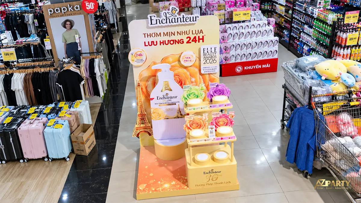 Booth vàng nhỏ nhìn từ trên cao cho thấy vách chai sữa tắm và kệ mẫu nhiều tầng