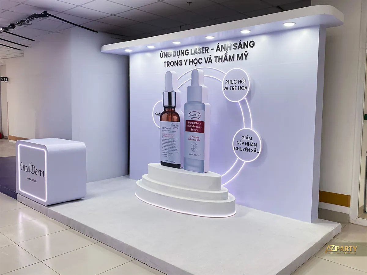 Góc chéo booth IntelDerm với bệ sản phẩm nhiều tầng và quầy nhận diện bên trái