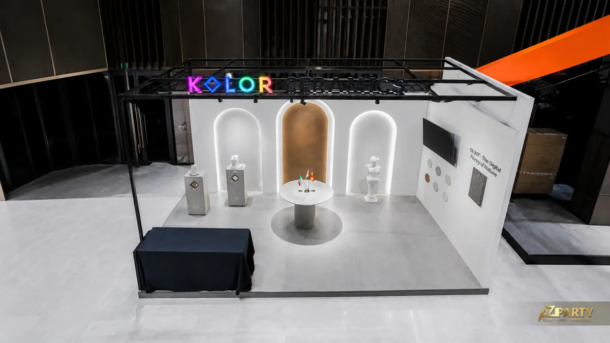 Góc chụp từ trên cao booth Kolor Ceramics với khung mái đen, logo thương hiệu và khu trưng bày sản phẩm tối giản