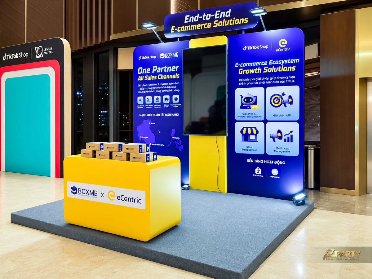 Góc nhìn bên trái booth Boxme với màn hình trung tâm và quầy trưng bày màu vàng