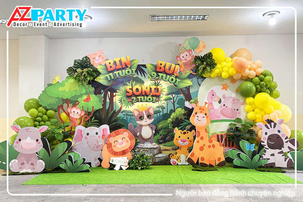 Trang trí tiệc sinh nhật chủ đề rừng xanh safari với backdrop 3D sinh động cho bé Sonij tròn 2 tuổi, kết hợp bóng bay nhiều màu sắc và mô hình các con vật dễ thương như hươu cao cổ, sư tử, tê giác.
