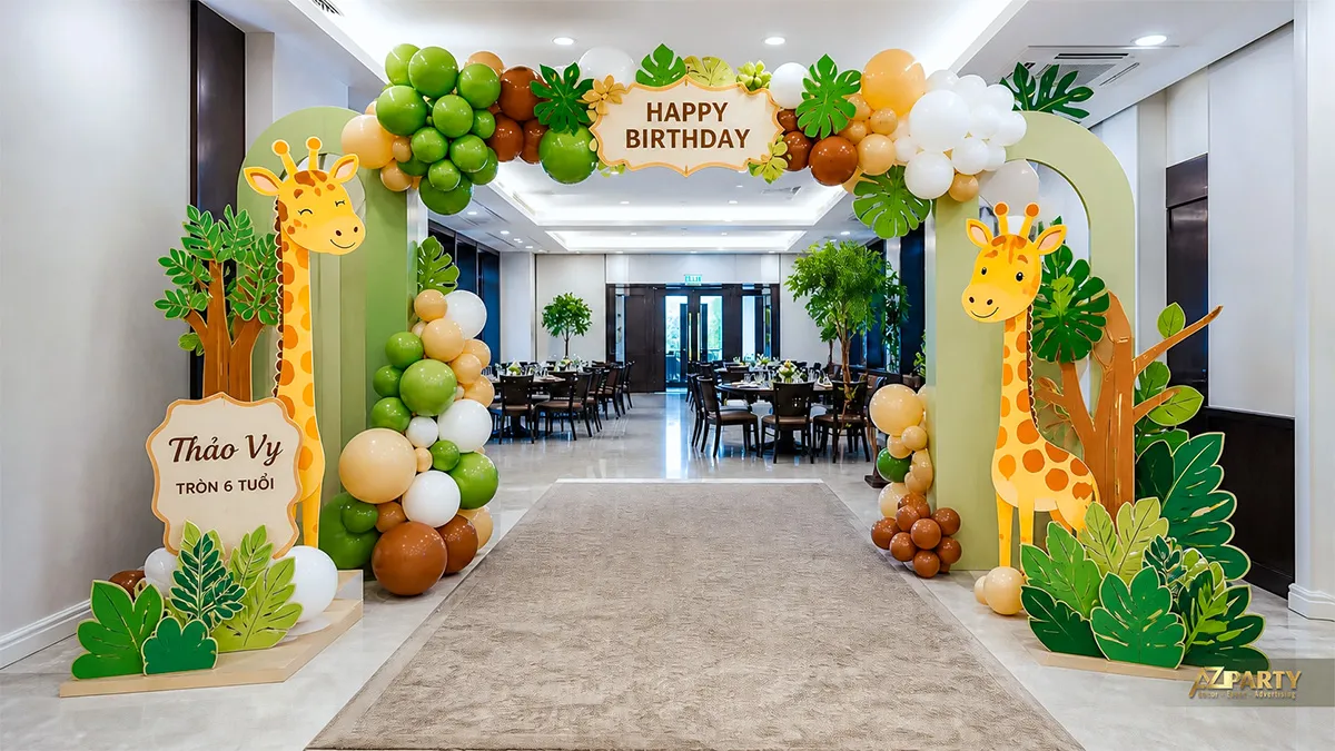 Cổng bóng sinh nhật chủ đề hươu cao cổ cho Thảo Vy tròn 6 tuổi, phối khung xanh kem, lá nhiệt đới và hai mô hình hươu.