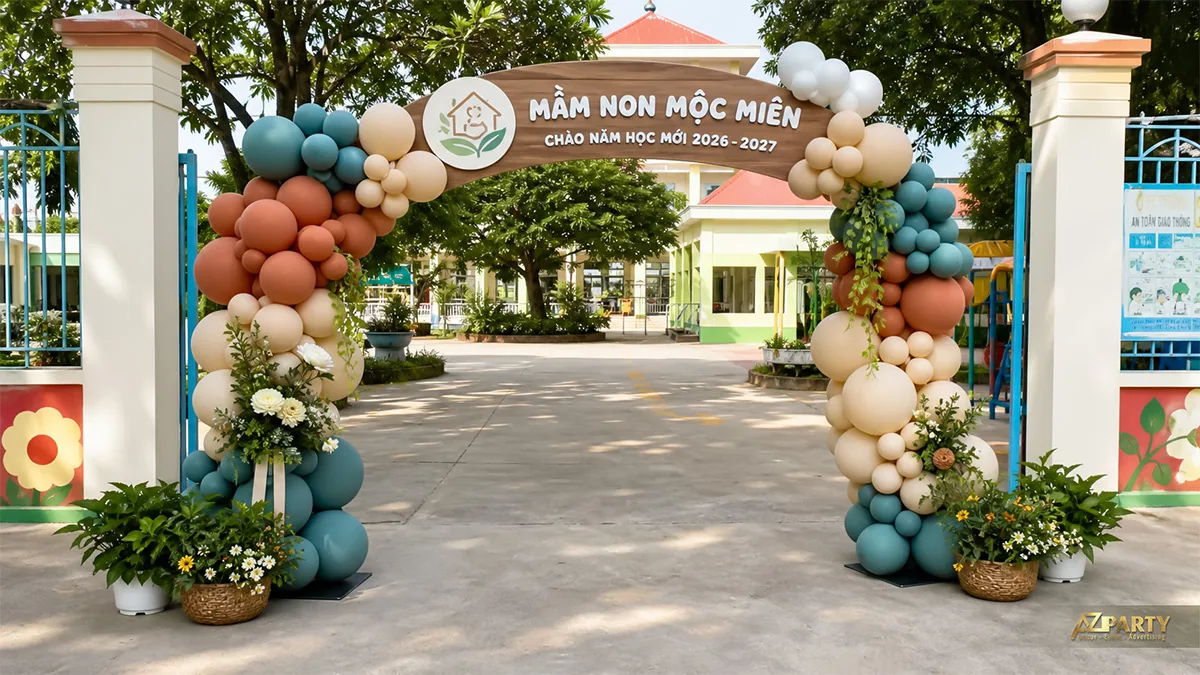 Cổng bóng màu đất xanh rêu kem với bảng gỗ và hoa trắng tại trường mầm non