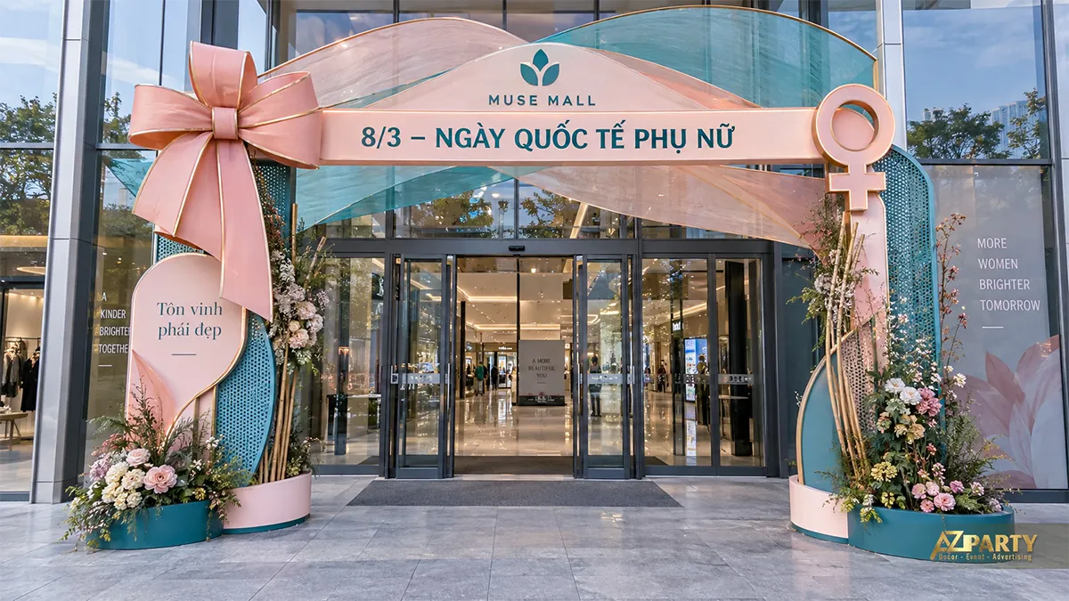 Cổng xanh ngọc phối hồng với nơ lớn và biểu tượng nữ ở hai góc