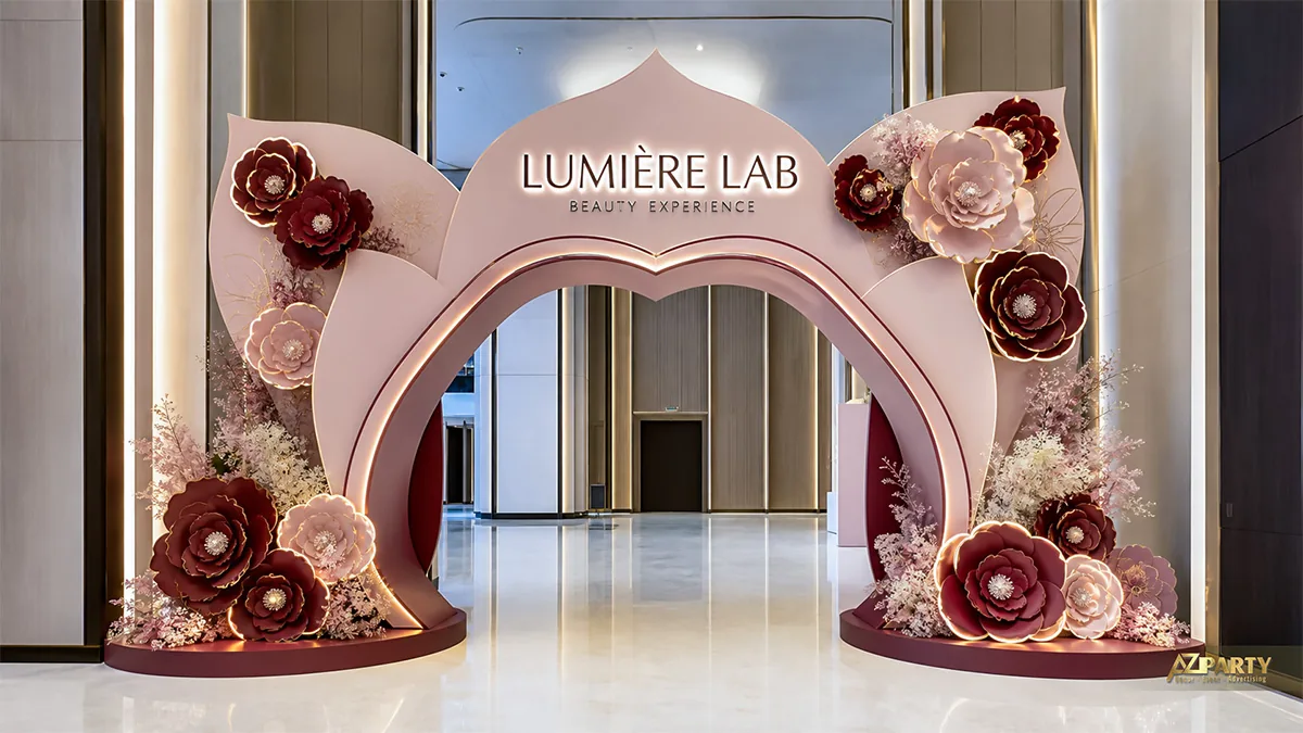 Cổng chào Lumière Lab màu hồng phấn, tạo hình cánh hoa và trang trí nhiều hoa nổi đỏ trắng