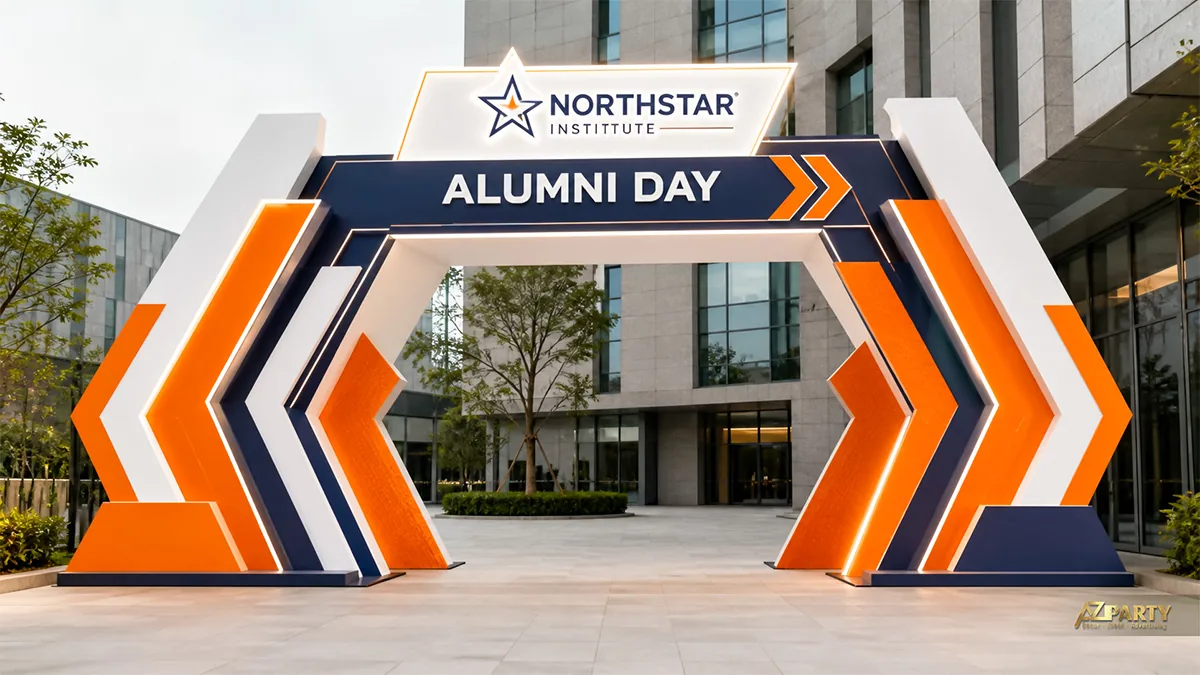 Cổng chào Alumni Day ngoài trời màu cam, xanh navy và trắng với các mũi tên lớn hai bên