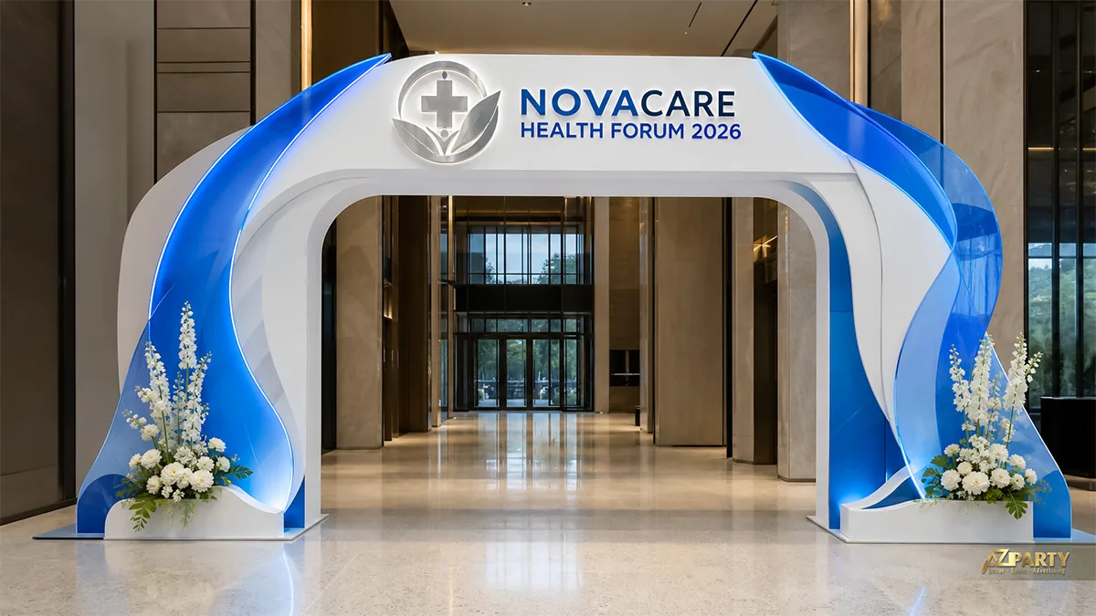 Cổng sự kiện NovaCare xanh trắng với hai dải cong ôm lối vào và cụm hoa trắng đặt dưới chân