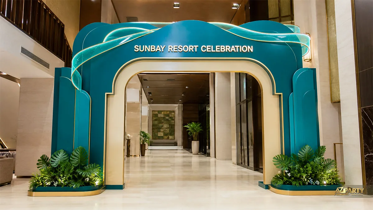 Cổng chào Sunbay Resort xanh ngọc phối kem, đường cong mềm và hai cụm lá nhiệt đới
