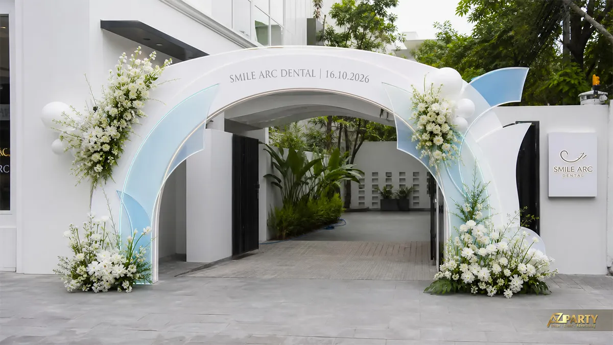 Cổng khai trương Smile Arc Dental màu trắng xanh nhạt với các cụm hoa trắng