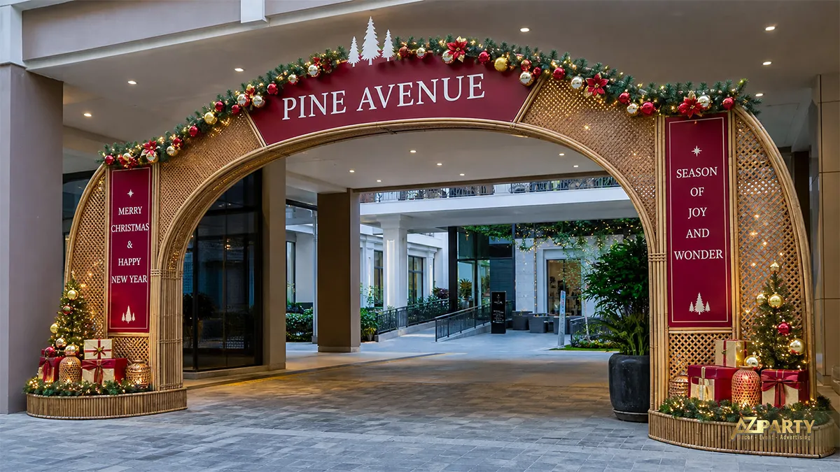 Cổng vòm màu đồng với mảng burgundy, dây thông, hộp quà và bảng Merry Christmas