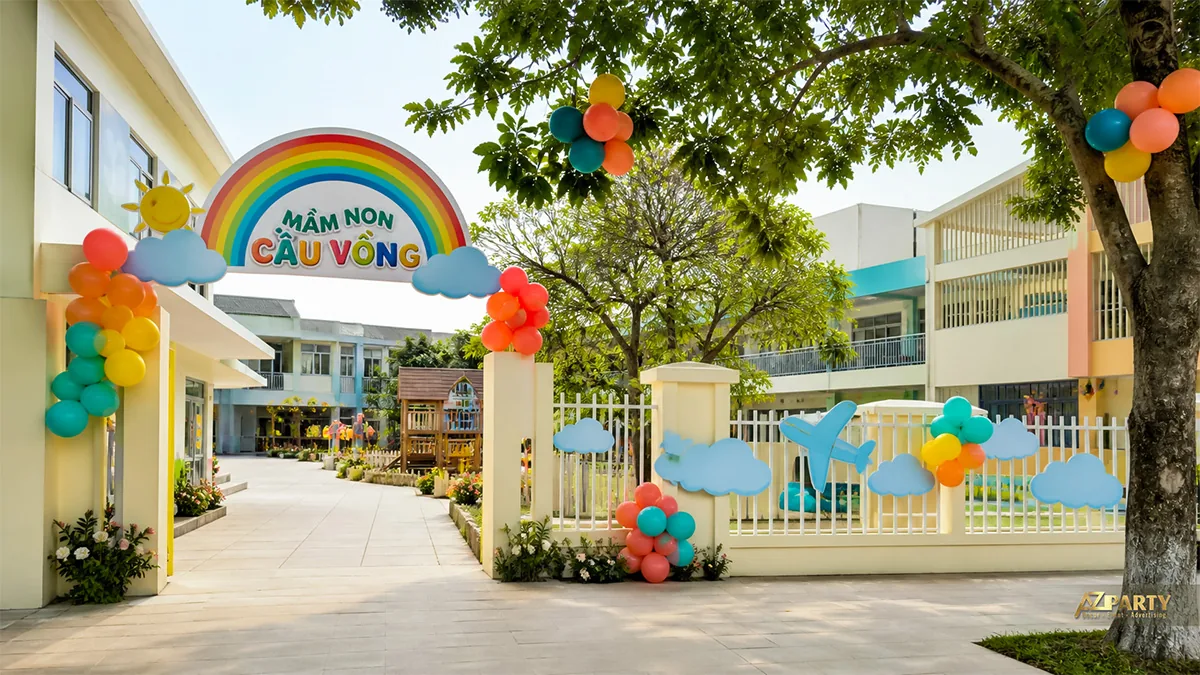 Cổng mầm non Cầu Vồng với mây, máy bay, bóng nhiều màu và sân chơi phía trong