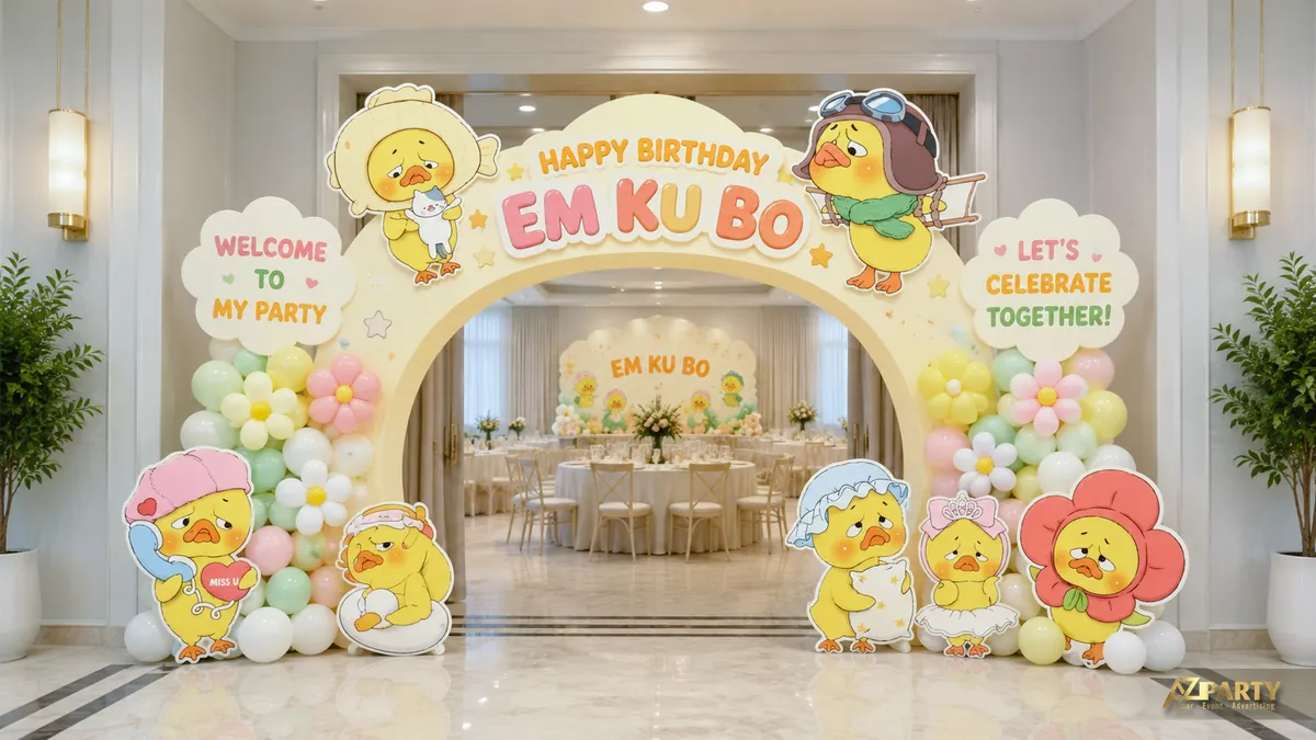 Cổng thôi nôi Em Ku Bo chủ đề vịt vàng với vòm pastel, standee nhân vật, hoa bóng và bảng welcome