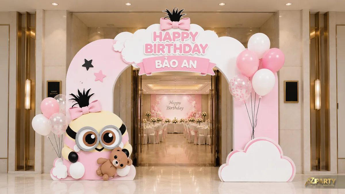 Cổng sinh nhật Bảo An tone hồng trắng với nhân vật minion, mây, bóng bay và backdrop tiệc phía trong