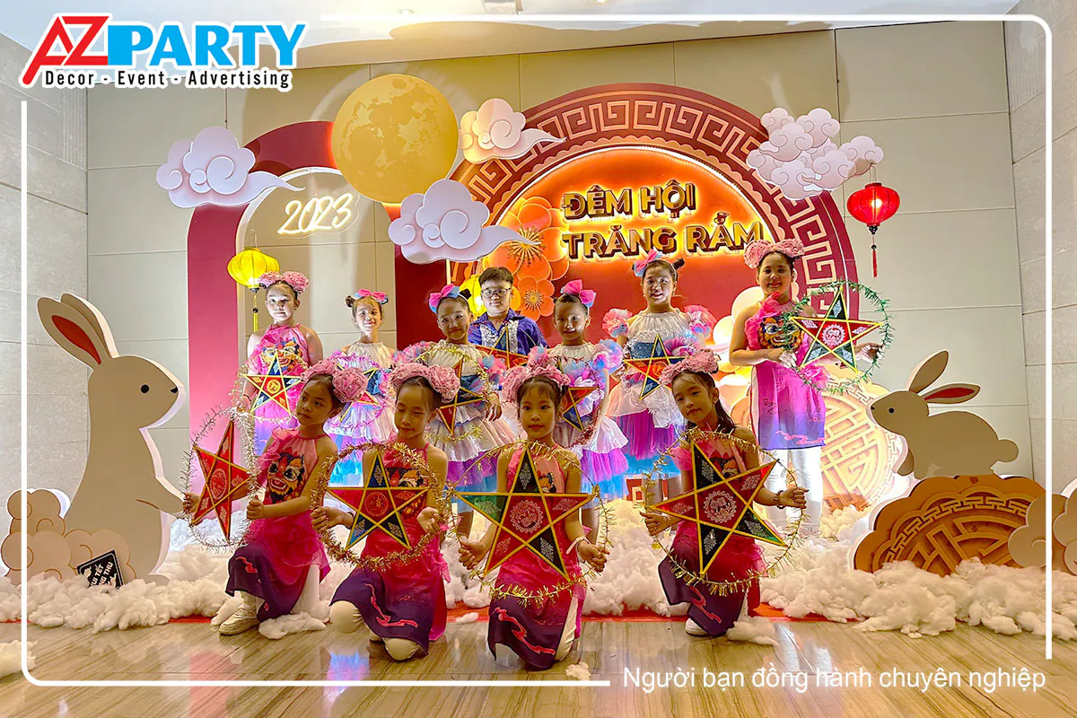 Các em thiếu nhi mặc trang phục hồng tím cầm đèn ông sao chụp ảnh kỷ niệm trước backdrop Đêm Hội Trăng Rằm 2023 NCSP