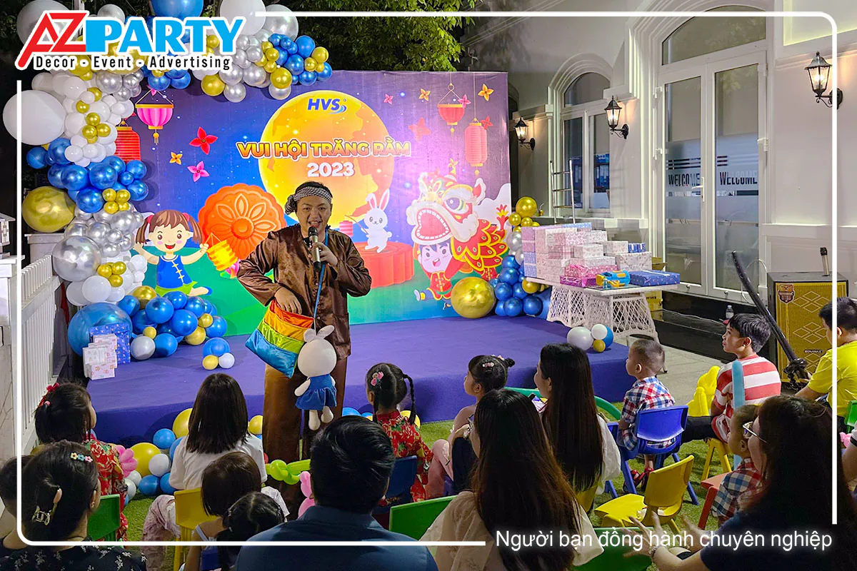 Chú Cuội đội khăn rằn giao lưu với các em nhỏ và phụ huynh ngồi bên dưới sân khấu Vui Hội Trăng Rằm HVS 2023