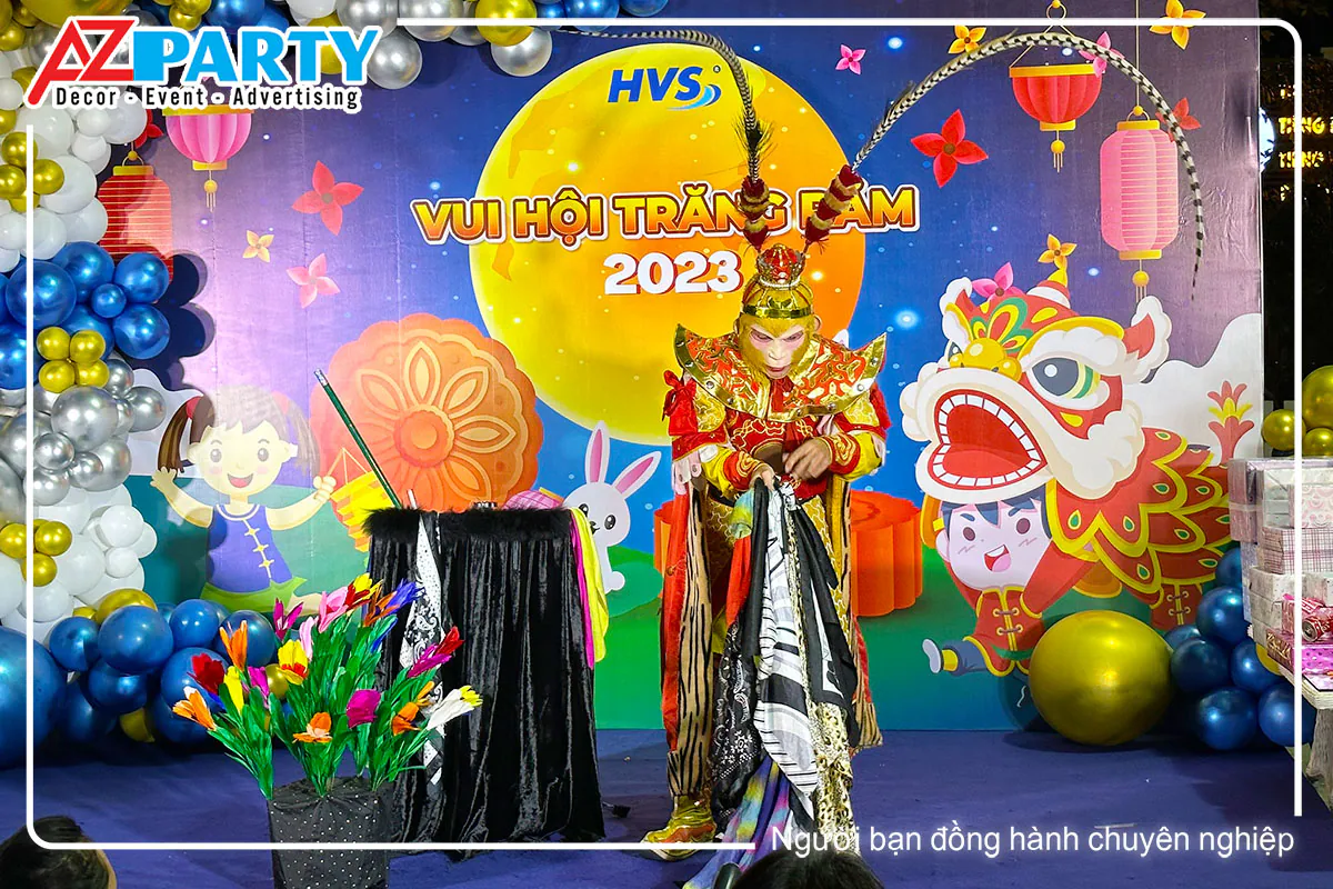 Tôn Ngộ Không mặc giáp vàng đỏ biểu diễn ảo thuật khăn trên sân khấu Trung thu HVS với hoa và bong bóng trang trí