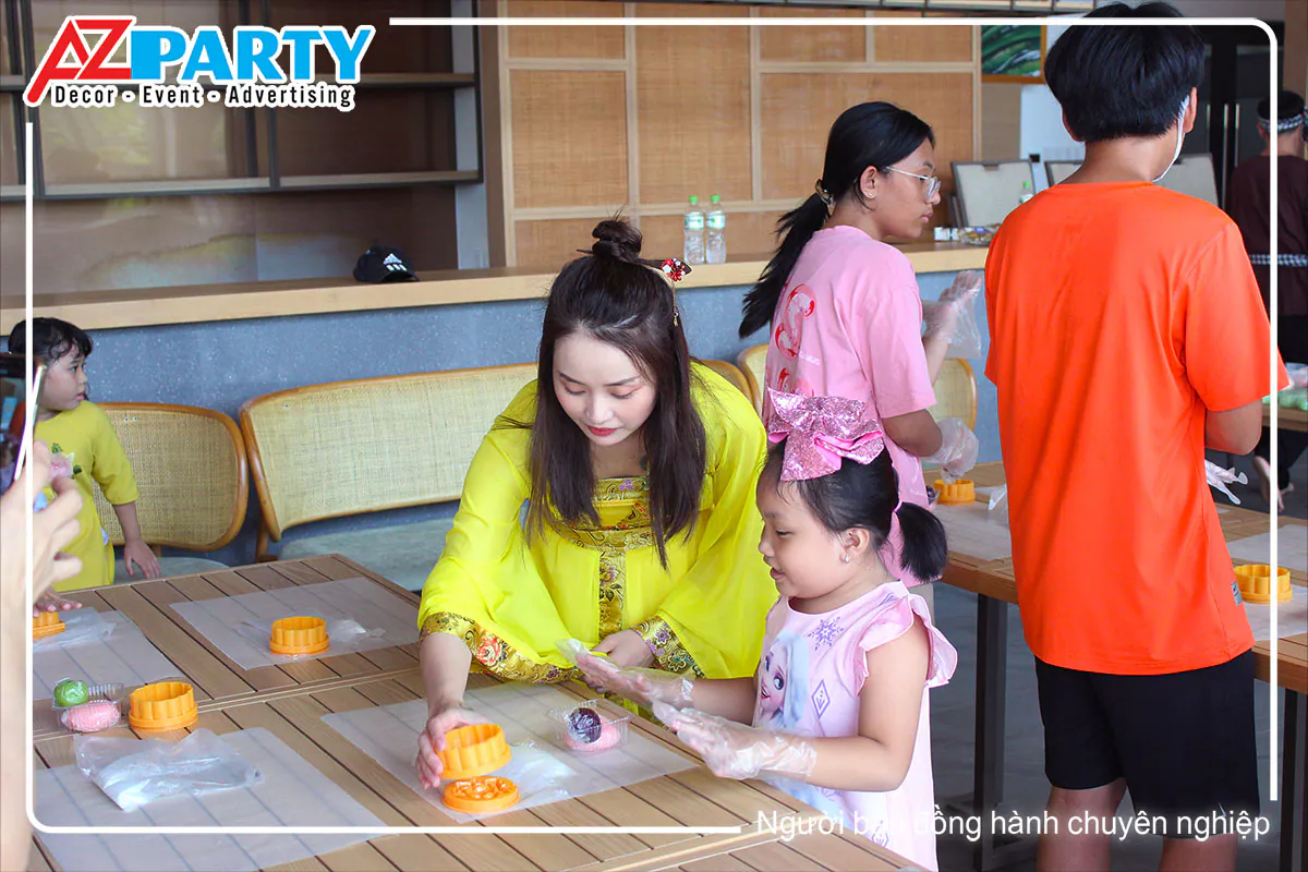 Chị Hằng xinh xắn tận tình hướng dẫn bạn nhỏ đóng khuôn tạo hình chiếc bánh dẻo trung thu.