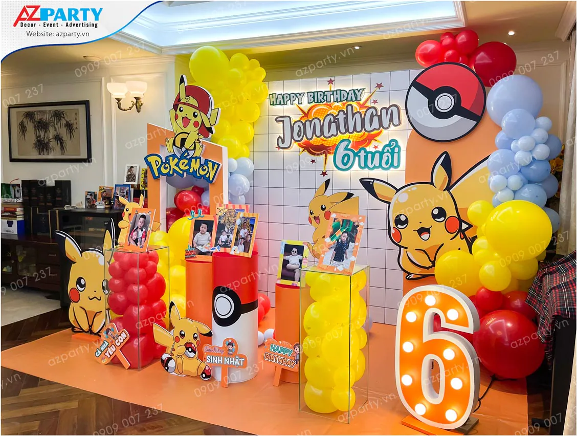 Góc nhìn nghiêng sân khấu trang trí thôi nôi sinh nhật chủ đề Pokemon cho bé Jonathan 6 tuổi, thể hiện sự bố trí hài hòa của các mô hình nhân vật và bóng bay nghệ thuật.