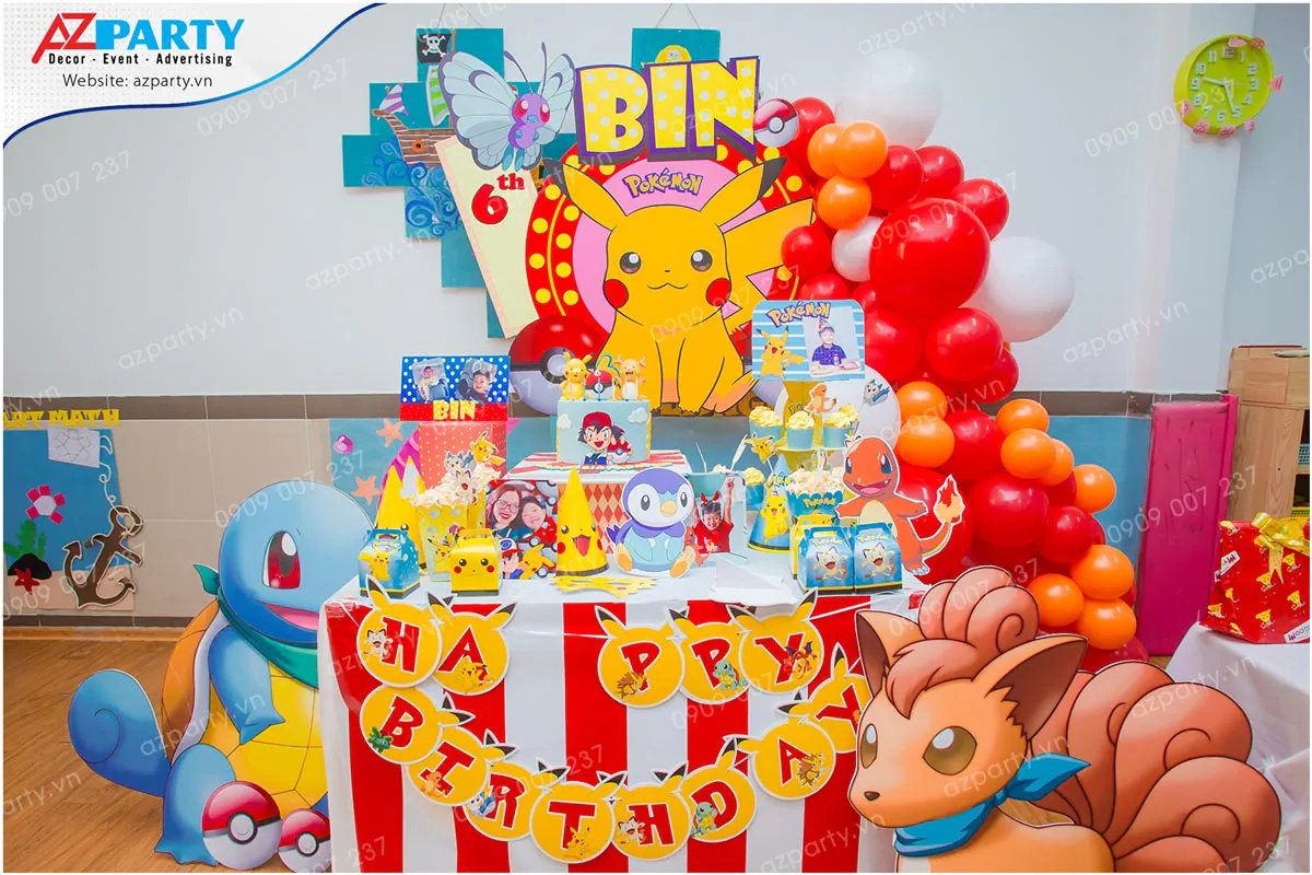 Trang trí tiệc sinh nhật bé Bin tròn 6 tuổi với chủ đề Pokemon sắc màu, có mô hình rùa nước Squirtle, cáo lửa Vulpix dễ thương, tháp bánh cupcake và cổng bong bóng màu đỏ, cam, trắng.