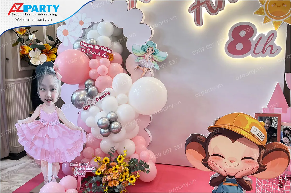 Góc trang trí bên trái sân khấu sinh nhật Khánh An với hình chibi dễ thương của bé mặc váy hồng múa ballet và cụm bóng bay màu hồng phấn, trắng đan xen.