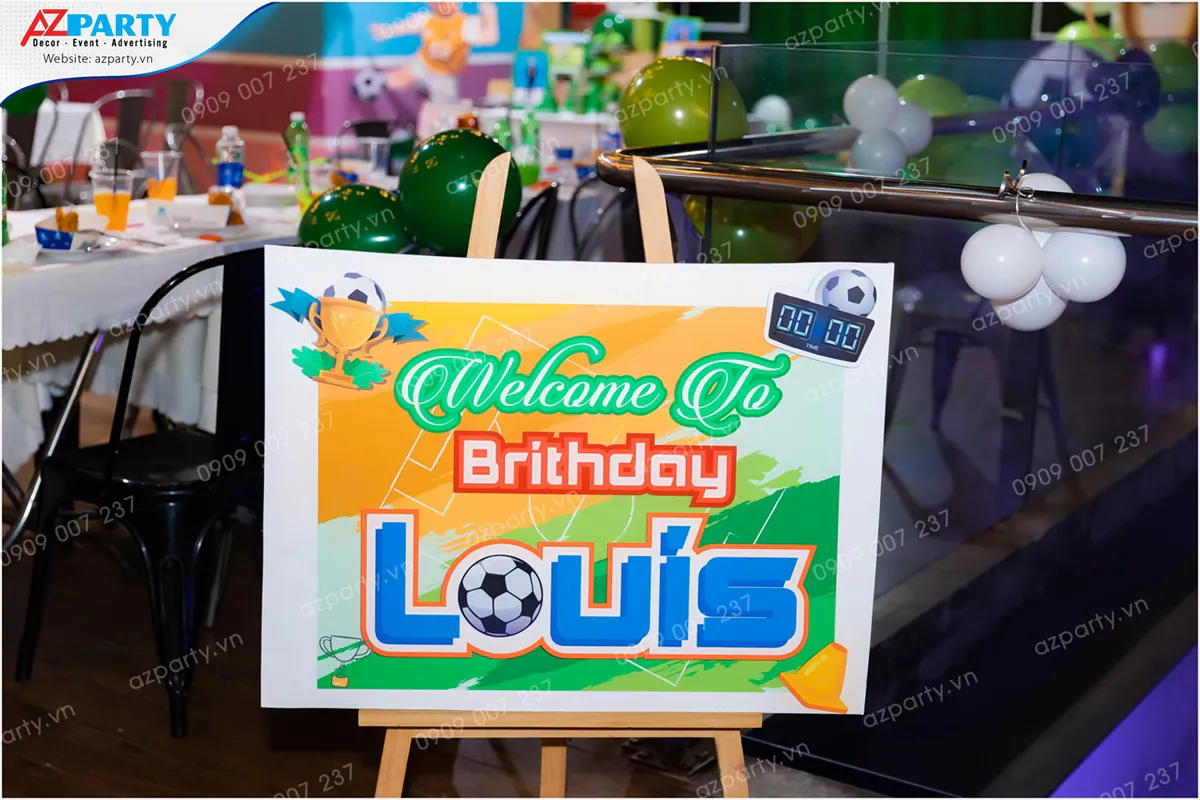 Bàn gallery bày trí các khung ảnh kỷ niệm của bé Louis cùng bánh cupcake kem xanh và nón sinh nhật xếp ngăn nắp.