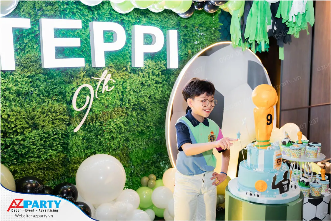 Bé Teppi vui vẻ cười tươi bên chiếc bánh kem sinh nhật tạo hình cúp vàng vô địch độc đáo trong tiệc mừng tuổi mới.
