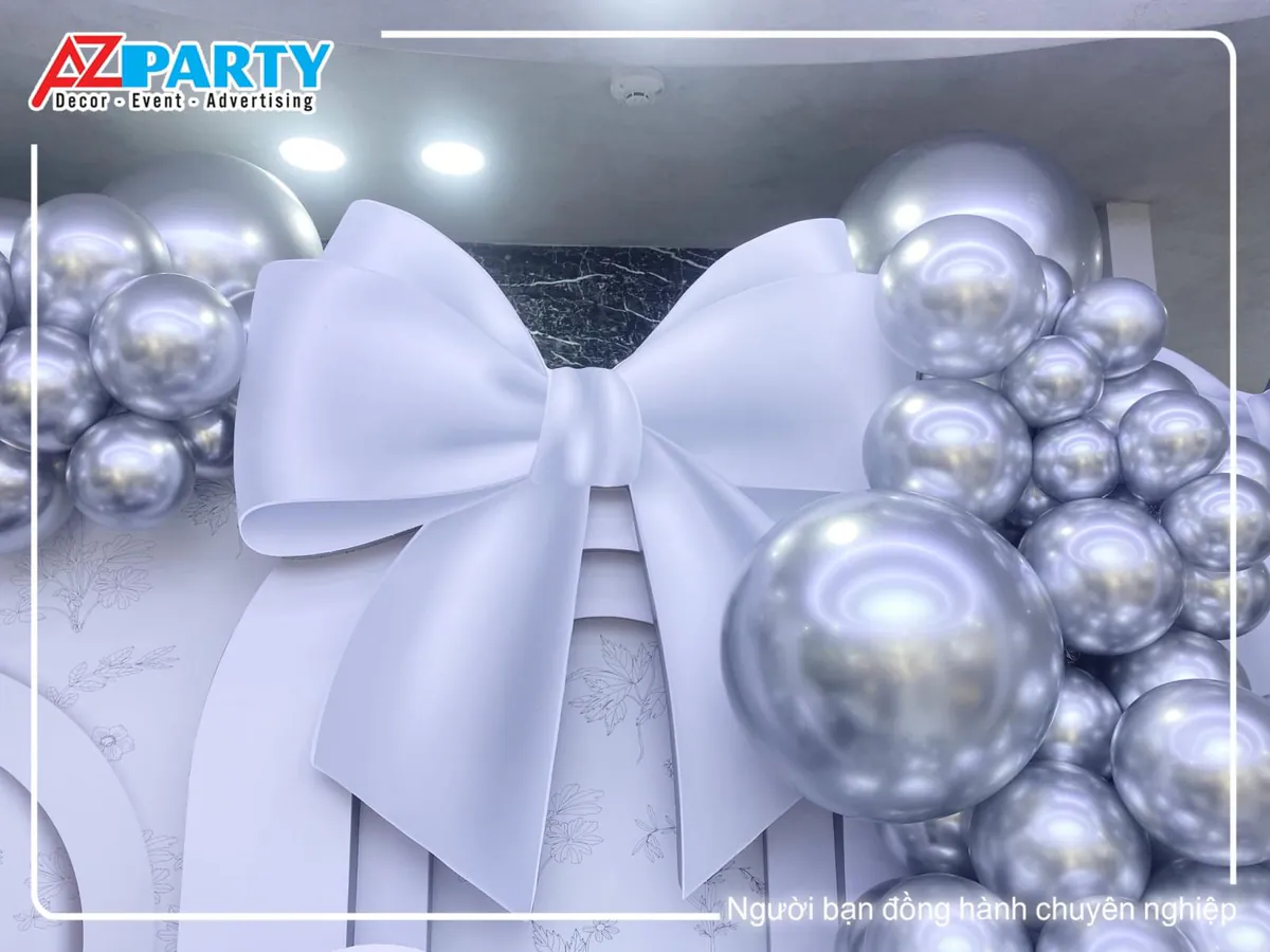 Mô hình chiếc nơ trắng khổng lồ làm điểm nhấn điệu đà trên tấm backdrop dạng vòm sang trọng