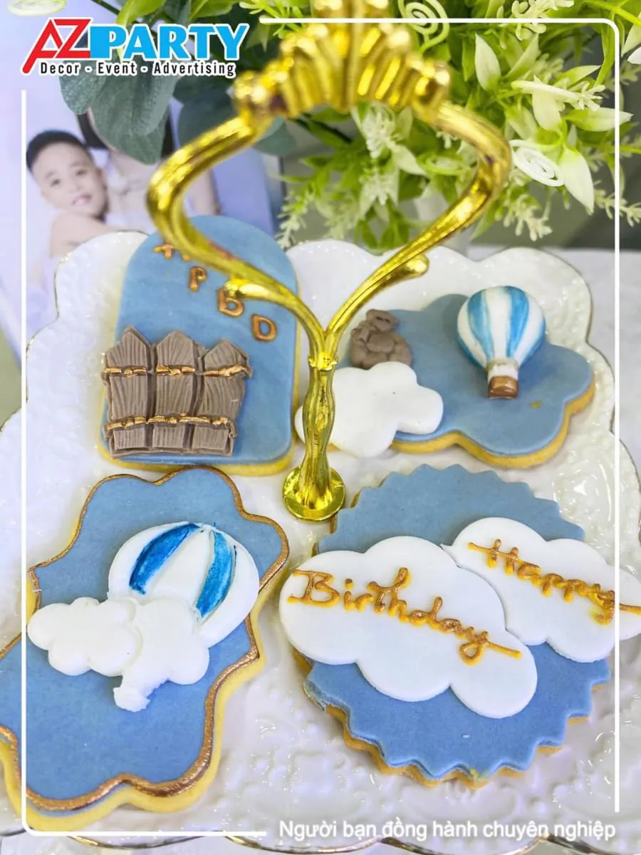 Đĩa bánh quy bơ vẽ đường icing chi tiết hình đám mây ghi chữ Happy Birthday và hình khinh khí cầu đáng yêu