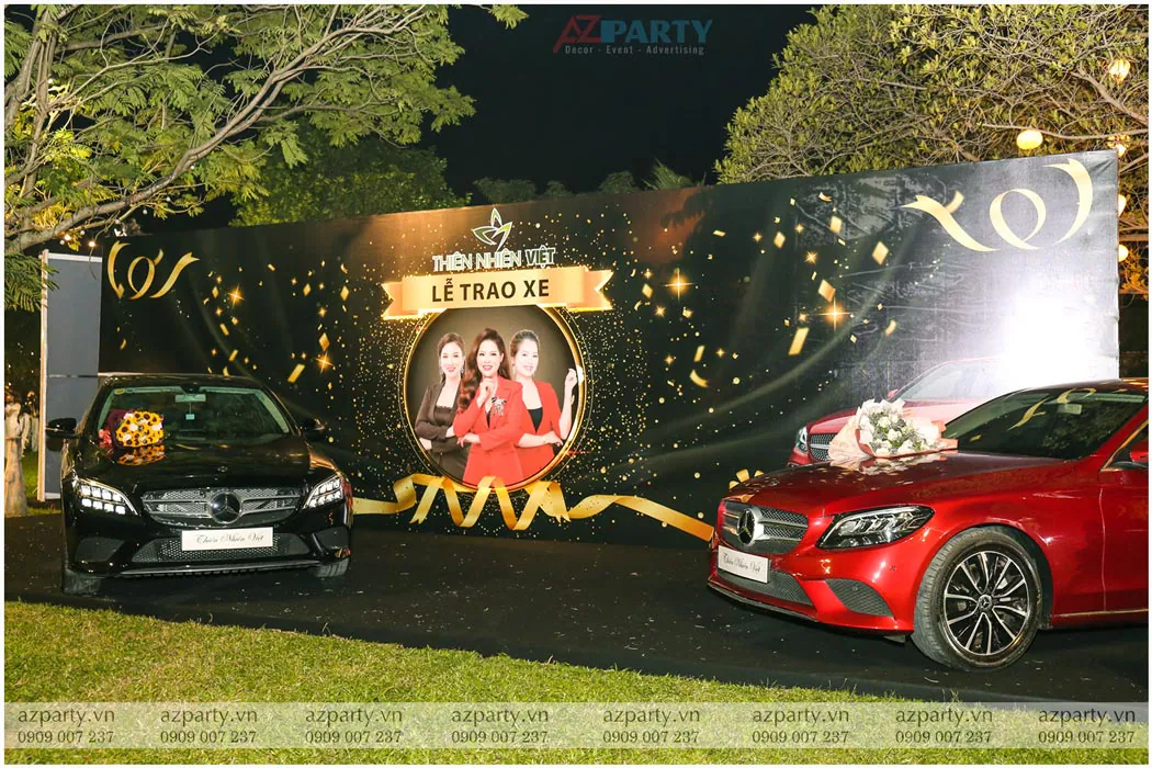 Khu vực lễ trao xe sang Mercedes-Benz với hai chiếc xe màu đen và đỏ đỗ trước backdrop sự kiện Thiên Nhiên Việt.