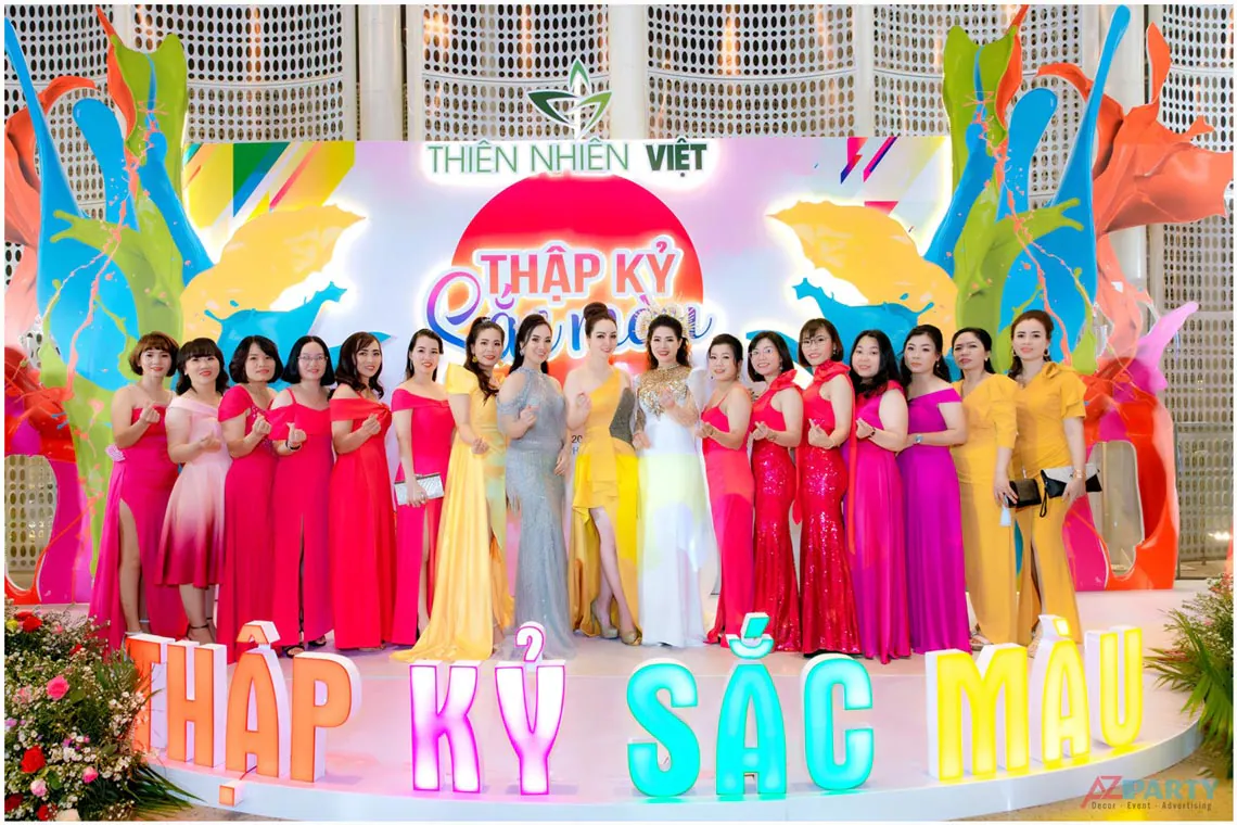 Dàn đại biểu xinh đẹp diện đầm dạ hội rực rỡ chụp ảnh lưu niệm trước backdrop 'Thập Kỷ Sắc Màu' của Thiên Nhiên Việt.