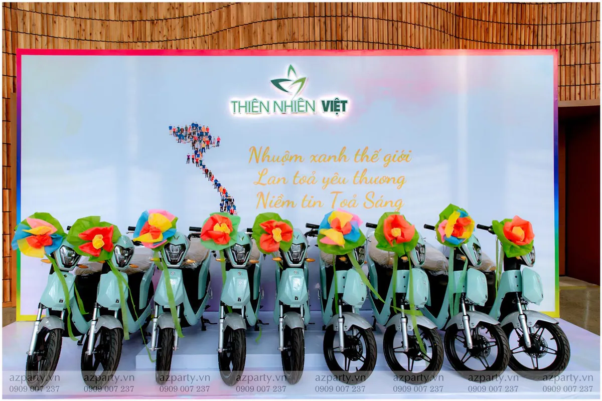 Dàn xe máy điện màu xanh ngọc làm phần quà tặng tri ân khách hàng trước backdrop ý nghĩa của Thiên Nhiên Việt.