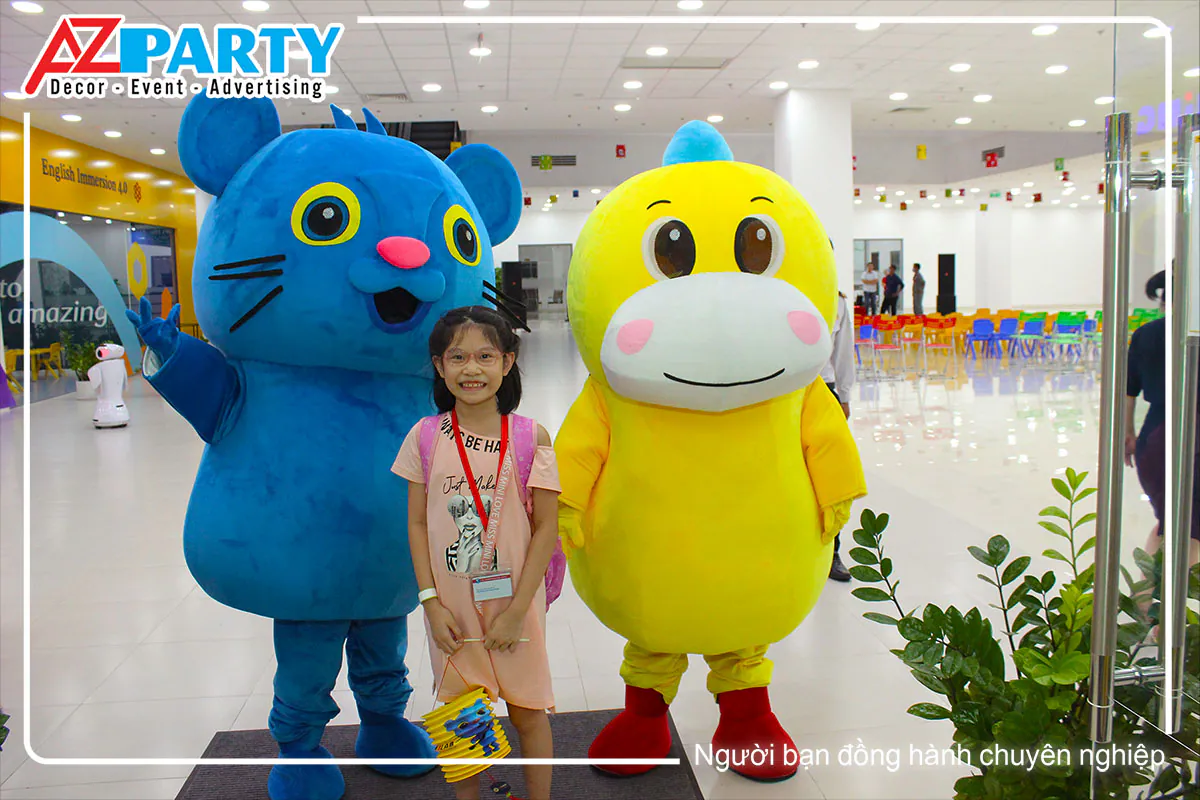 Bé gái xinh xắn chụp hình kỷ niệm cùng hai chú mascot gấu thân thiện tại cổng chào sự kiện.