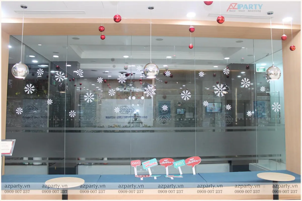 Vách kính văn phòng công ty COSCO trang trí decal bông tuyết trắng kết hợp các bóng châu đỏ thả trần và hashtag chụp hình Noel.